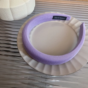 Detail of purple knitted fabric headband with handmade label on ceramic plate