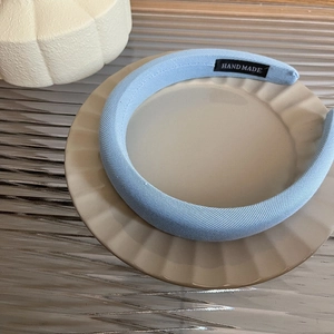 Detail view of light blue padded sponge headband with handmade label on ceramic plate