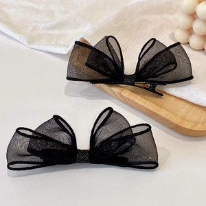 Détail de barrettes noeud en tulle noir avec paillettes sur un plateau en bois clair