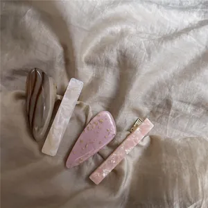 Macro shot of assorted acetate hair clips with marble and floral patterns on silk fabric