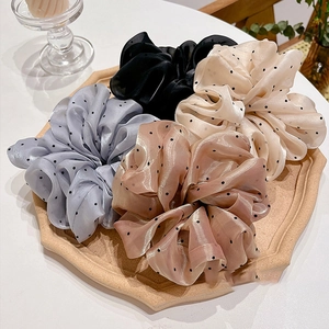 Gros plan de chouchous géants en organza à pois en quatre couleurs pastel sur un plateau