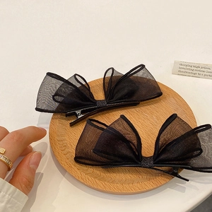Barrettes à cheveux élégantes avec nœuds en résille noire sur un plateau en bois naturel