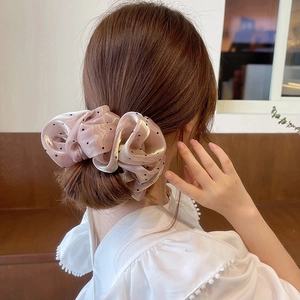Gros plan sur un grand chouchou en organza rose à pois sur la queue-de-cheval d'une fille