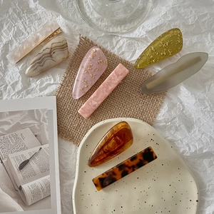Macro shot of high-quality acetate hair clips with marble and amber patterns in soft colors