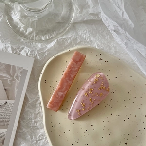 Detail of pink marble resin hair clip and gold leaf glitter hairpin in a ceramic tray