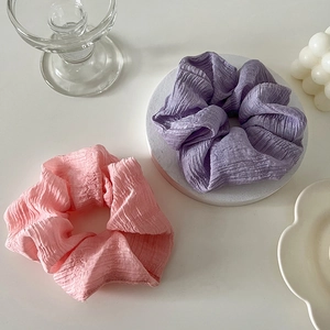 Détail de chouchous en mousseline plissée rose et violet sur fond blanc épuré