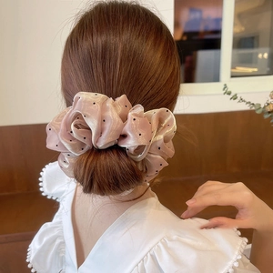 Vue arrière d'un grand chouchou rose à pois coiffé dans un chignon de femme