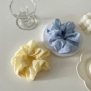 Détail de chouchous en tissu texturé jaune crème et bleu clair au style plissé
