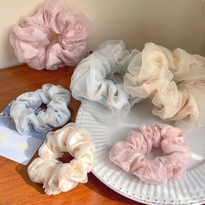 Set of 6 floral organza scrunchies in pastel colors on a wooden table display