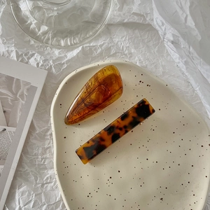 Close-up of elegant amber resin and tortoiseshell patterned hair clips on a ceramic tray