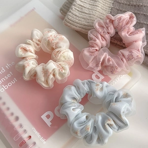 Three-piece set of mesh scrunchies featuring daisy floral patterns and layered textures