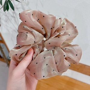 Détail d'un grand chouchou en organza champagne à pois noirs avec un éclat métallique