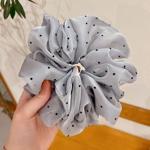 Détail d'un chouchou gris à pois fabriqué dans un tissu soyeux brillant de haute qualité