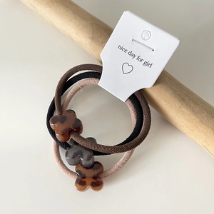 Detailed macro shot of three leopard print acrylic clover hair ties on a display card