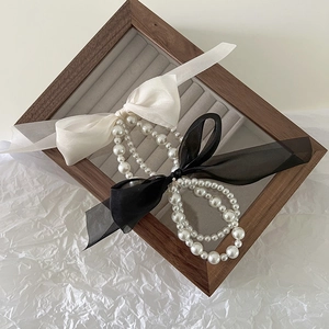 Elegant pearl bow hair scrunchies in black and white styles on a grey display tray