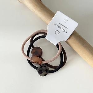 Close-up of leopard print acrylic beads on elastic hair ties in beige and black colors