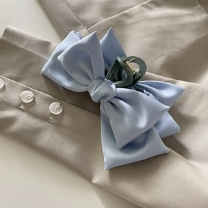 Gros plan d'une pince à cheveux avec nœud en satin bleu clair sur tissu beige