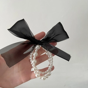 Detail of double-layer pearl elastic band with black organza bow for hair or wrist
