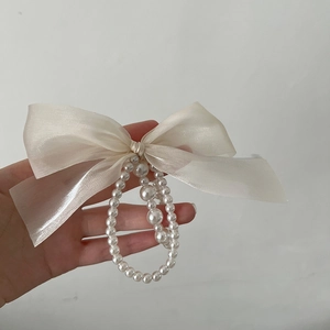 Detailed macro view of cream organza bow hair tie with layered pearl bead center