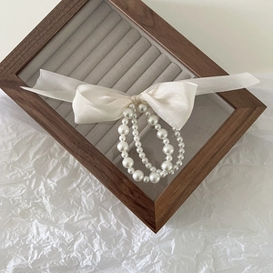 Detailed macro view of white pearl hair tie and soft silk bow on a luxury jewelry box