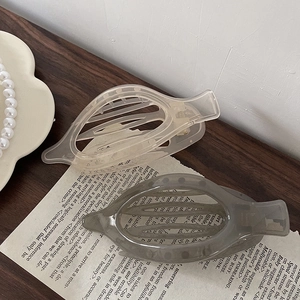 Detail of leaf-shaped acrylic hair claws in translucent cream and smoky grey tones