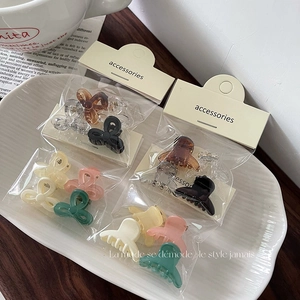 Set of colorful jelly transparent mini bow hair clips in a white ceramic tray