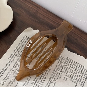 Detailed view of a transparent brown acrylic hair claw clip on a stylish vintage background