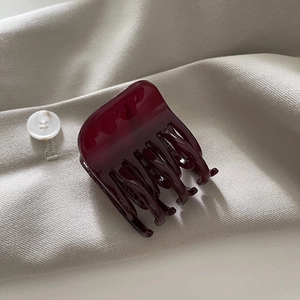 Vue détaillée d'une pince à cheveux rouge foncé brillante sur un tissu beige