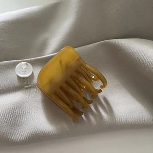 Pince à cheveux élégante en acétate ambré sur un fond en tissu doux texturé