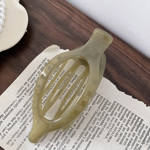 Detail of olive green resin hair claw clip with teeth structure on a vintage book