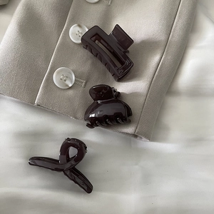 Detailed view of three coffee-colored hair claws in geometric and twisted resin designs