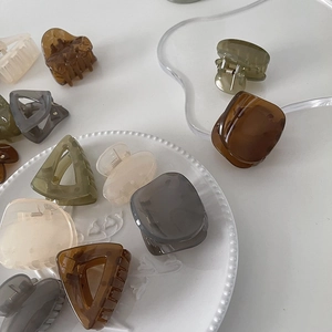 Minimalist geometric resin hair clips in neutral tones on white aesthetic prop plate