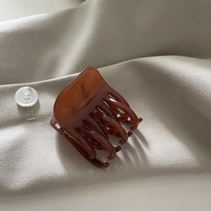 Vue détaillée d'une pince à cheveux en acide acétique marron sur tissu beige