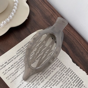 Close-up of a grey translucent acrylic hair clip with hollowed design on vintage paper