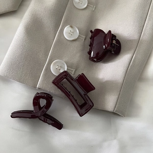 Three elegant burgundy resin hair clips displayed on a beige blazer for stylish hair styling