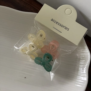 Close-up of 4 mini translucent butterfly hair clips in mixed colors on a white plate