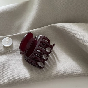 Détail d'une pince à cheveux en acétate bordeaux montrant les dents polies et le ressort