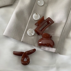 Three elegant amber resin hair claws shown on a beige blazer for a French minimalist style