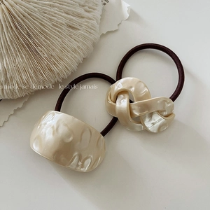 Close-up of beige resin hair ties with hammered texture and twisted knot designs