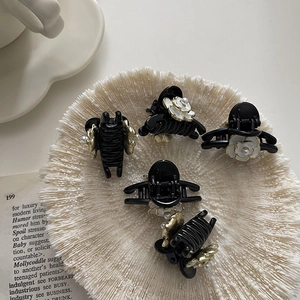 Detail of five mini camellia hair clips with pearls and flowers in a white decorative tray