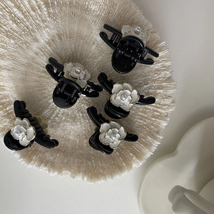 Detail of five mini camellia hair claws with white petals and pearls on a white tray