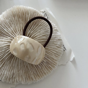 Retro cream beige hammered resin hair tie with a dark brown elastic cord on coral