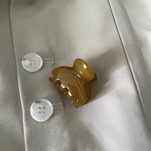 Detail of amber translucent cross hair claw clip placed on beige blazer fabric