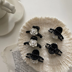 Five-piece matte black camellia flower hair claws with pearls on a vintage styled background