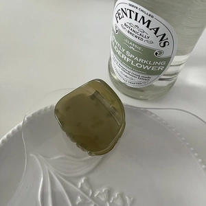 Detail of a dark olive green semi-transparent mini hair claw clip on a white ceramic plate