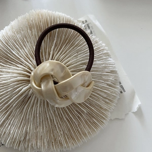 Detailed macro view of cream marble resin twist knot decoration on a brown elastic hair tie