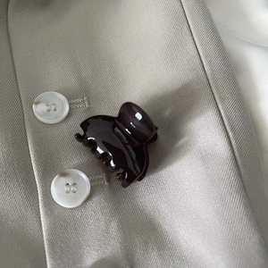 Detailed view of mini tortoiseshell hair claw clip on a stylish beige blazer texture