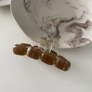 Detail view of amber texture hair claw clip with square beads on white background