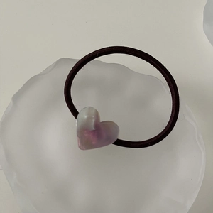 Close-up of a purple heart-shaped resin charm on an elastic hair tie in a white tray