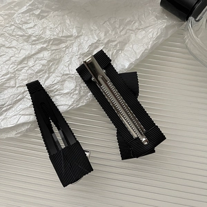 Dettaglio di due fermagli per capelli neri rivestiti in nastro con base in metallo argento